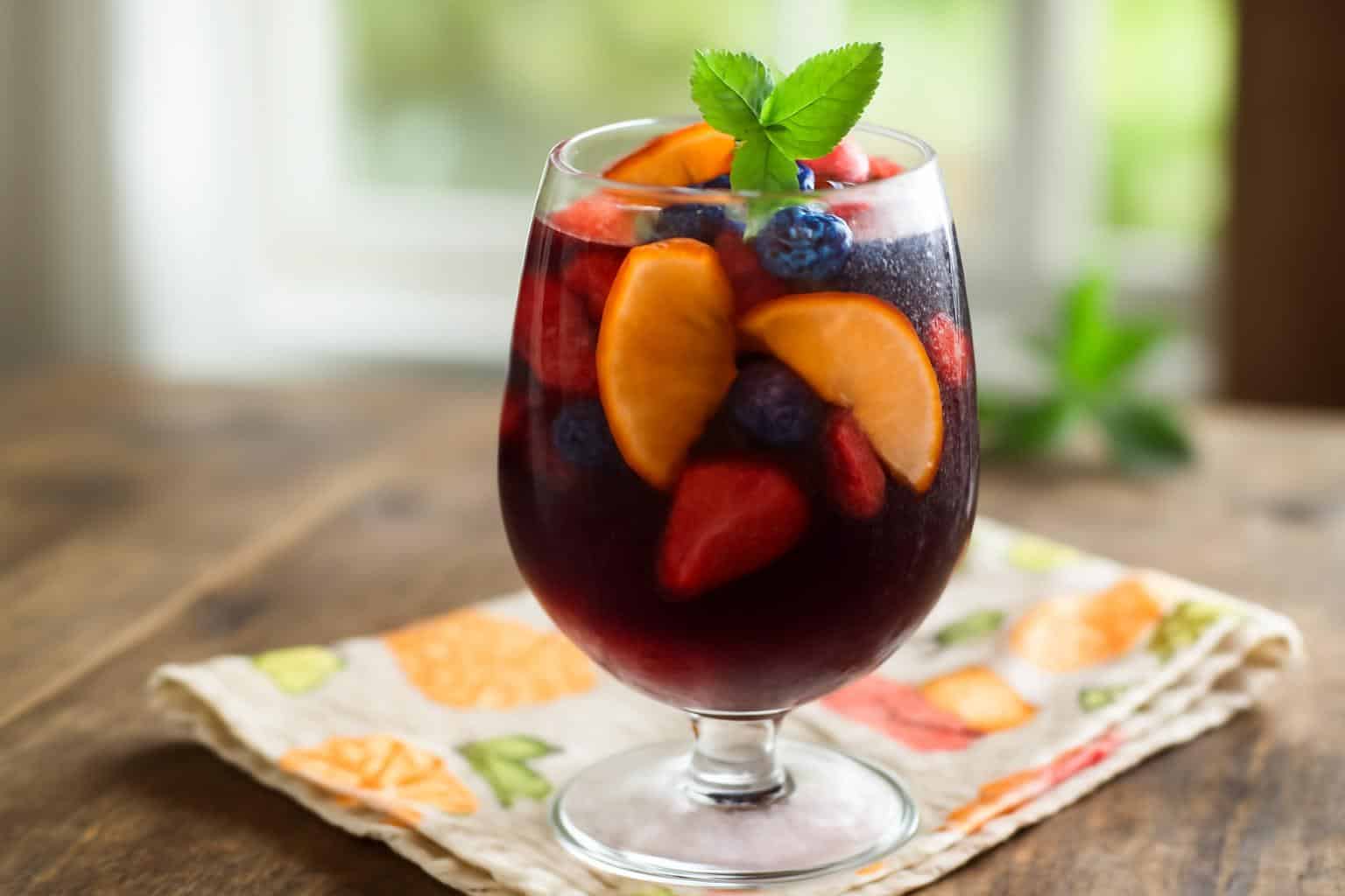 Glass of summer sangria with fresh fruit slices and mint garnish, showcasing summer sangria recipes
