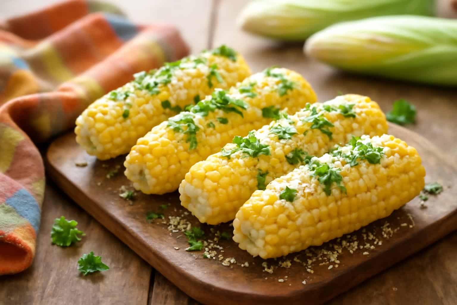 grilled garlic parmesan corn on the cob garnished with parsley and parmesan cheese