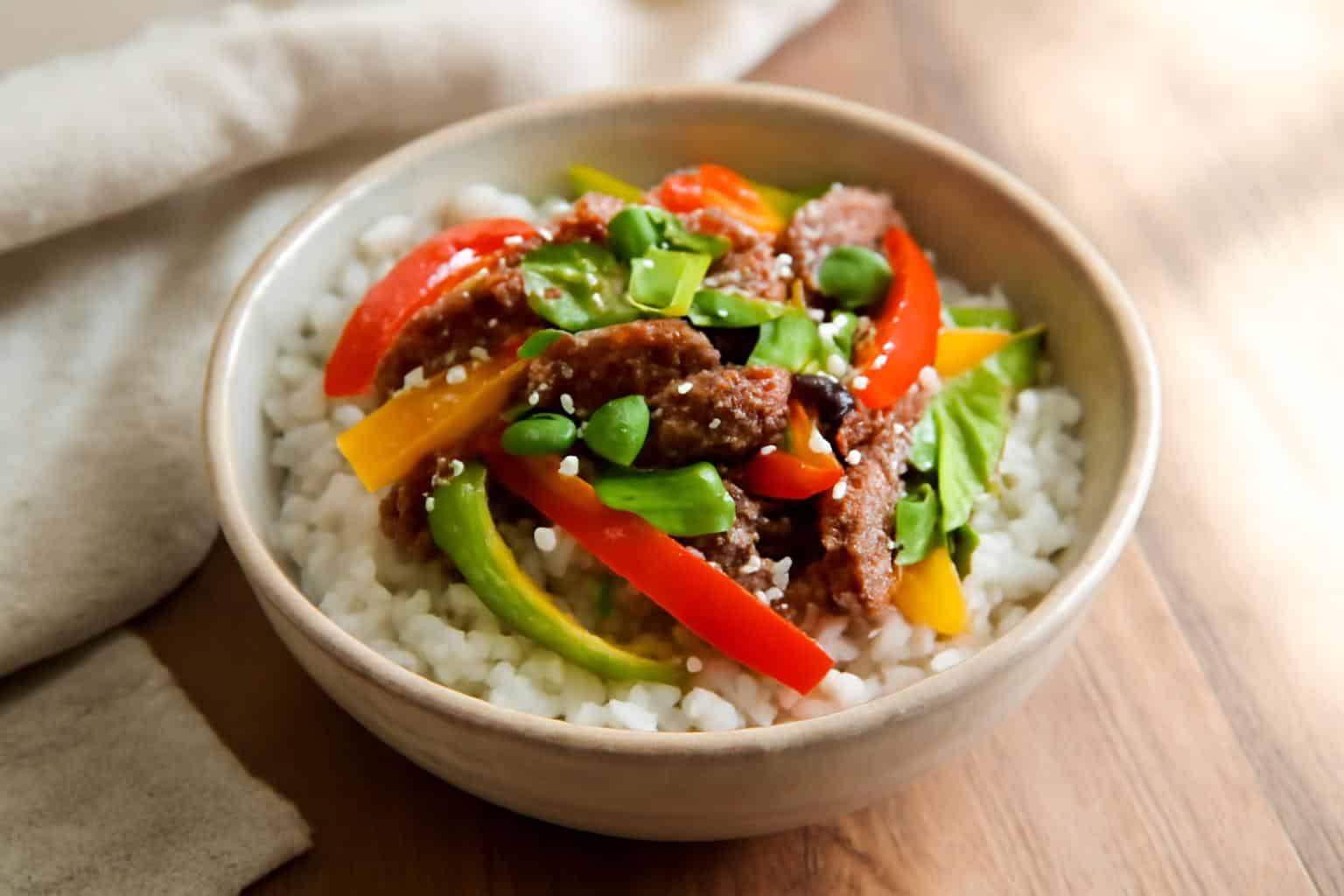 Savory beef pepper rice bowl with colorful bell peppers and fluffy white rice, garnished with scallions