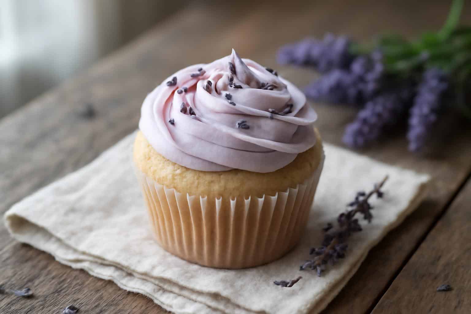 Delicious lavender cupcakes with pale purple frosting and lavender garnish on rustic wooden surface