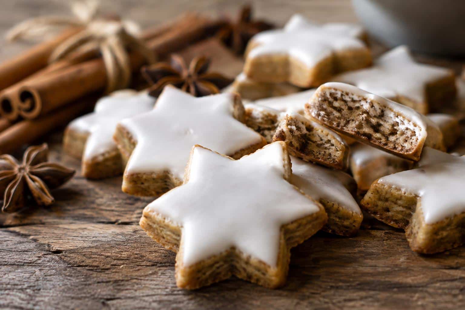 Freshly baked cinnamon stars cookies with white glaze on rustic wooden surface, traditional German cinnamon stars