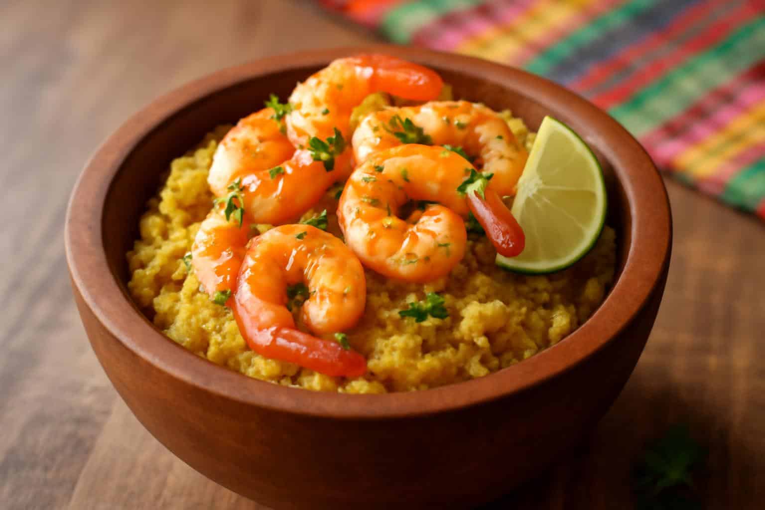 Sizzling garlic shrimp mofongo served in rustic bowl garnished with parsley and lime wedge