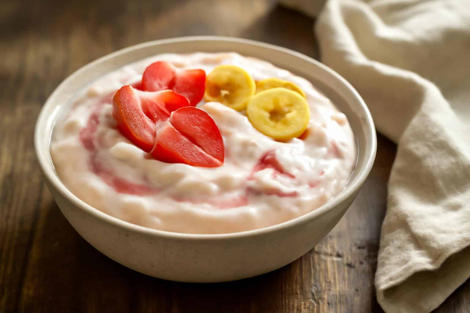 Creamy strawberry cheesecake banana pudding dessert garnished with fresh strawberries and banana chips