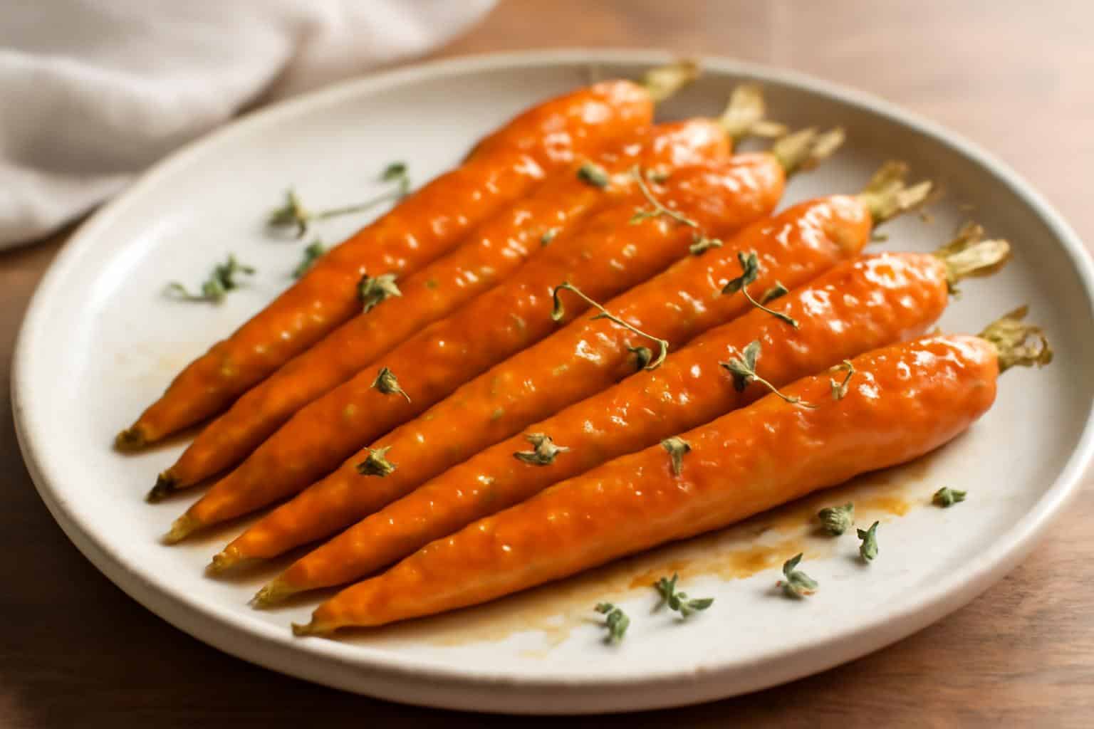 Maple mustard glazed carrots served on a rustic plate with fresh thyme garnish